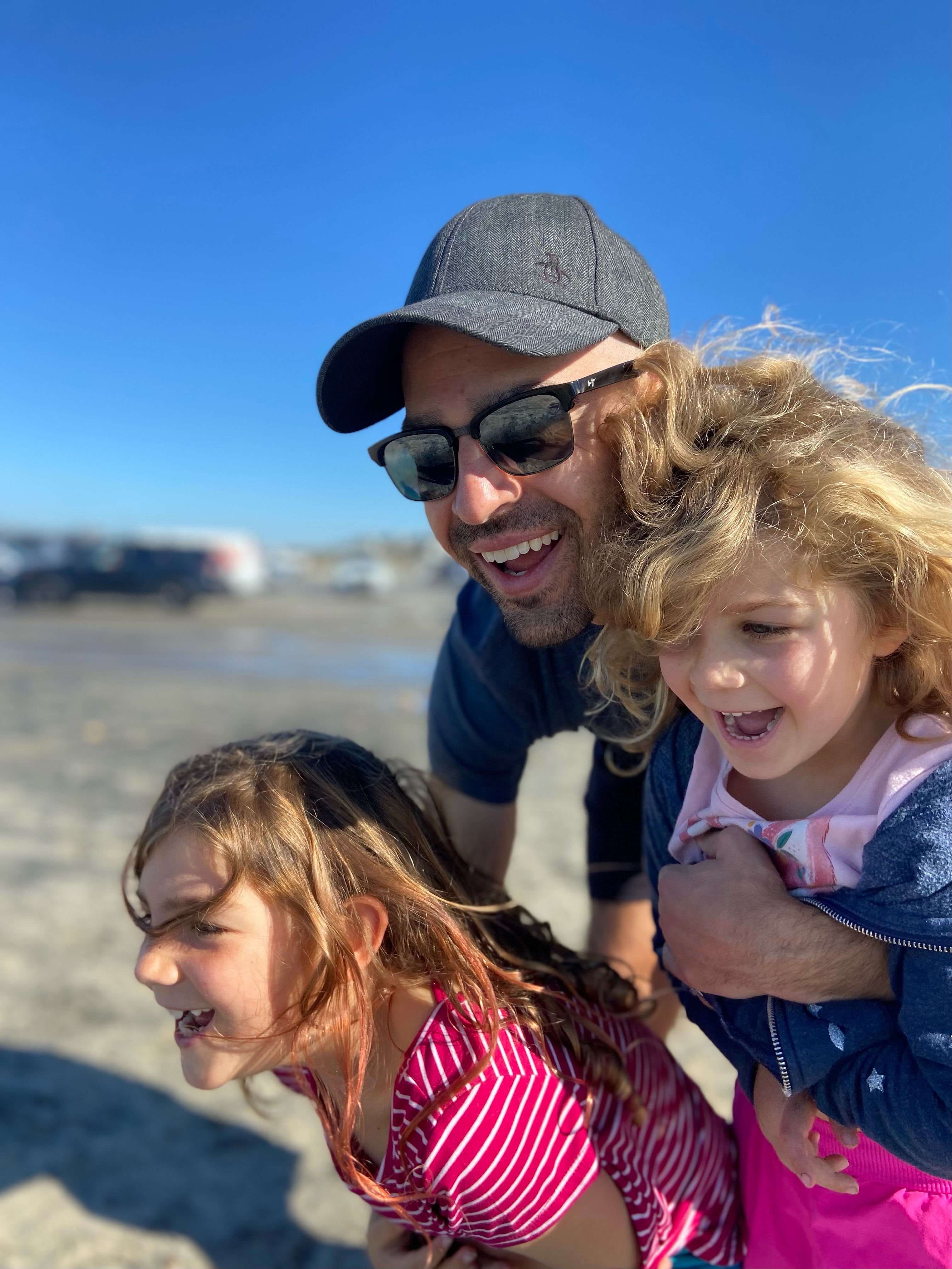 Micah Lueck laughing on the beach with his two daughters